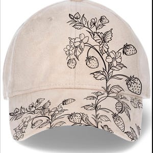 May include: A beige baseball cap featuring a black floral design with strawberries and flowers. The design is on the front and the brim of the cap. The cap has a curved brim and a button on top.