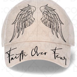 May include: A beige baseball cap featuring black angel wings and the words "Faith Over Fear" in a script font. The cap has a curved brim and a rounded crown, suitable for casual wear.