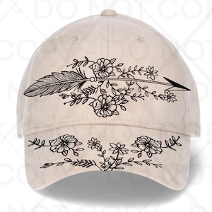 Puede incluir: Gorra de béisbol beige con un diseño de flecha floral y pluma negra. La flecha está compuesta por una pluma, flores y hojas. La visera de la gorra tiene un diseño floral a juego.