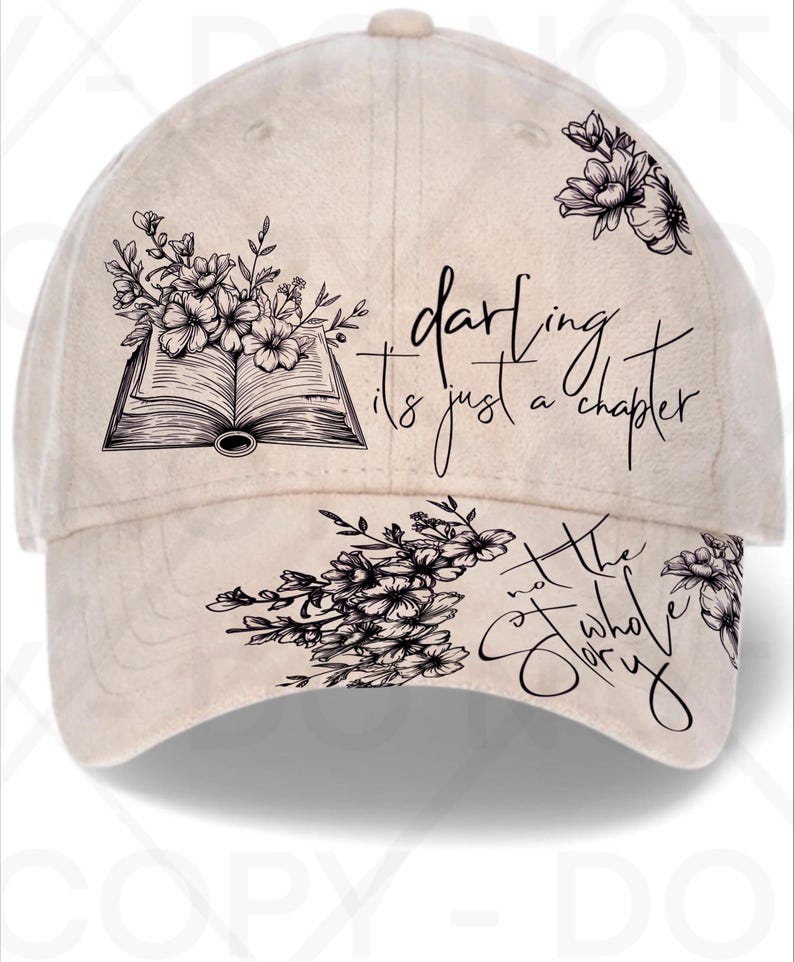 May include: Beige baseball cap with floral and book graphics. The cap features the text "darling it's just a chapter, not the whole story" in black script. The cap has a curved brim and a button on top.