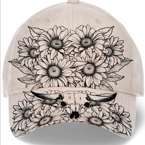 Könnte beinhalten: Beige Baseballkappe mit einem schwarz-weißen Blumendesign und einem Bullenschädel. Das florale Design umfasst Sonnenblumen und Blätter. Die Kappe hat einen gebogenen Schirm und einen Knopf oben.