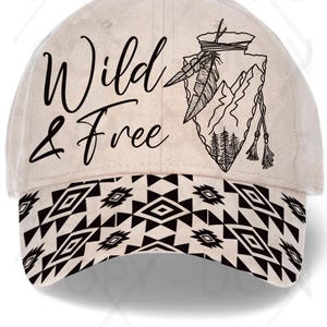 May include: A beige baseball cap with the words "Wild & Free" in black script. The cap features a black and white geometric pattern on the brim and a black graphic of a mountain, feathers, and trees.