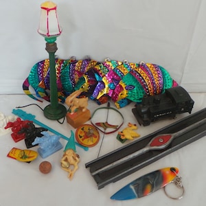 May include: A collection of vintage toys and trinkets, including a miniature street lamp, a toy train, a small wooden rabbit, a metal armadillo, a toy duck, a small wooden horse, a toy car, a small wooden gnome, a small metal carousel, a small metal mirror, a small metal key chain, and a small metal train track.