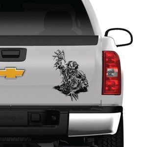 May include: A white pickup truck with a black and white zombie decal on the back window. The truck has a silver Silverado emblem on the tailgate.
