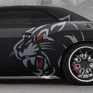 May include: A black car with a large, fierce-looking panther graphic on the side. The panther is grey with red eyes and a menacing expression.
