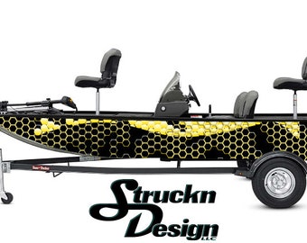 Può includere: Una barca nera e gialla con un motivo a nido d'ape sul lato. La barca è su un rimorchio con un logo in bianco e nero che dice "Struckn Design LLC".
