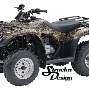 Puede incluir: Un ATV negro con un patrón de piel de serpiente, cuatro ruedas y un portaequipajes de metal negro en la parte trasera. El ATV tiene un asiento negro y un volante negro. El ATV está sobre un fondo blanco. El texto "Struckn Design" es visible en el lateral del ATV.