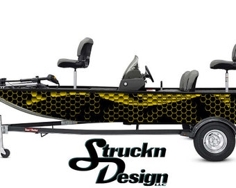 Può includere: Una barca nera e gialla con un motivo a nido d'ape sul lato. La barca è su un rimorchio con un logo in bianco e nero che dice "Struckn Design LLC".