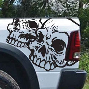 Op de afbeelding: Zwart-witte schedel sticker voor een vrachtwagen. De sticker heeft twee schedels, een bovenop de andere, met een gedetailleerd ontwerp.