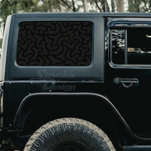 May include: Black Jeep Wrangler with a custom window decal featuring a black and gray abstract pattern. The decal covers the entire rear window.