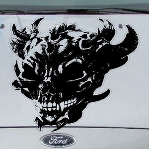May include: Black and white skull decal with horns and a detailed design. The skull has a menacing expression with sharp teeth and a prominent jawline.