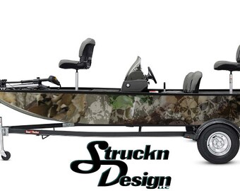 Puede incluir: Un barco de pesca con estampado de camuflaje con un diseño de calavera, en un remolque con un logotipo en blanco y negro que dice "Struckn Design LLC".