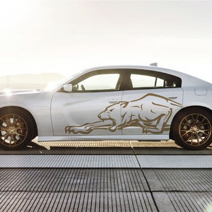 May include: A white Dodge Charger with a gold-colored graphic of a stylized panther on the side of the car.