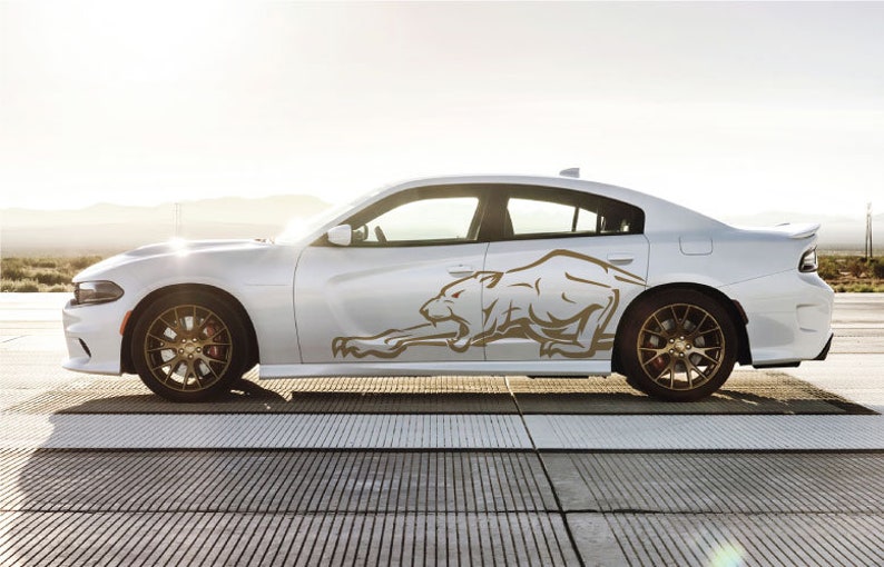 May include: A white Dodge Charger with a gold-colored graphic of a stylized panther on the side of the car.