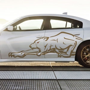 May include: A white car with a brown graphic of a snarling animal on the side. The animal has a white body and a brown outline.