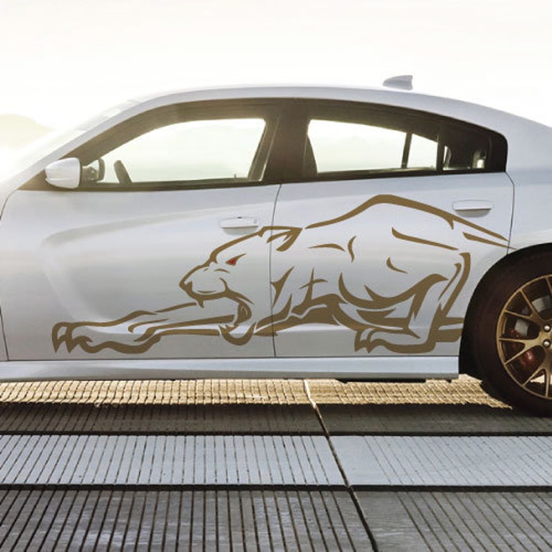 May include: A white car with a brown graphic of a snarling animal on the side. The animal has a white body and a brown outline.