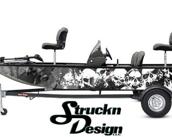 Puede incluir: Una lancha de pesca negra y gris con un diseño de calaveras. La lancha tiene dos asientos grises, un motor Mercury y está sobre un remolque. El diseño de la lancha incluye el texto "Struckn Design".