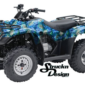 May include: A blue and green patterned ATV with black wheels and a black roll cage. The ATV has a black seat and a black rear rack. The ATV is on a white background.