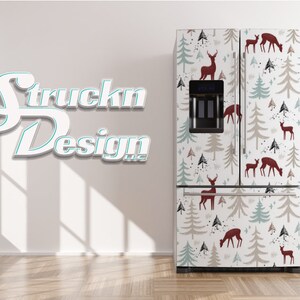 May include: A white refrigerator with a removable vinyl wrap featuring a repeating pattern of stylised green and beige trees and red deer. The wrap has a white background with black splatters of paint.