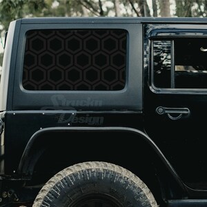 May include: Black Jeep Wrangler with a black honeycomb pattern window decal. The decal covers the rear window of the vehicle.