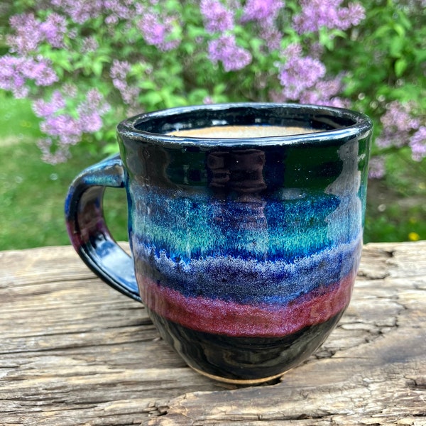 Pottery coffee cup made by hand on potters wheel of stoneware clay with 5 multi color glazes brushed on and signature of studio potter maker