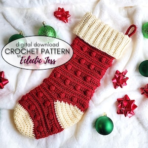 May include: A red and cream crochet stocking with a bobble stitch pattern. The stocking has a cream cuff and a loop at the top. The stocking is surrounded by red and green ornaments and bows.
