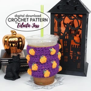 May include: Crochet pumpkin coffee cozy in purple with orange pumpkins. The cozy is on a coffee cup with a straw. The text "digital download CROCHET PATTERN by Eclectic Jess" is in a white oval.