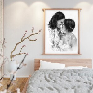 May include: A black and white pencil drawing of a couple embracing. The drawing is framed in a light wood frame and is hanging on a white wall.