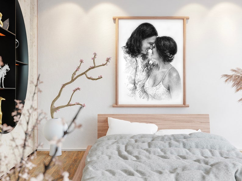 May include: A black and white pencil drawing of a couple embracing. The drawing is framed in a light wood frame and is hanging on a white wall.