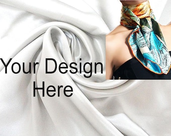 May include: A white silk scarf with a colorful floral pattern. The scarf is tied around the neck of a person wearing a black top. The text "Your Design Here" is printed on the white silk fabric.