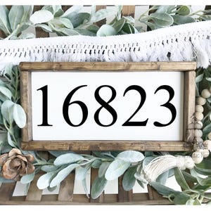 May include: A wooden sign with a white background and black lettering. The sign reads "16823".