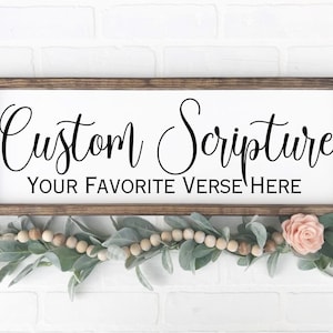 May include: A rectangular wooden sign with a dark brown frame and a white center panel. The text reads Custom Scripture in a black cursive font, with the text YOUR FAVORITE VERSE HERE in a black sans-serif font below it.