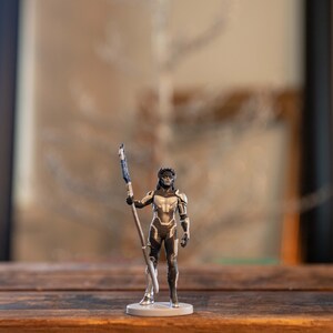 May include: A silver and black action figure of a female character holding a staff. The figure is standing on a gray base.