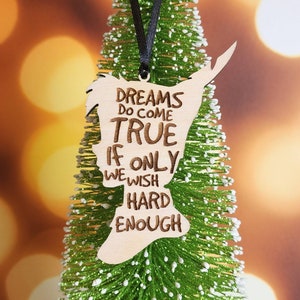 以下が含まれることがあります： 「Dreams do come true if only we wish hard enough」というテキストが書かれた、人の頭の形をした木製クリスマスオーナメント。