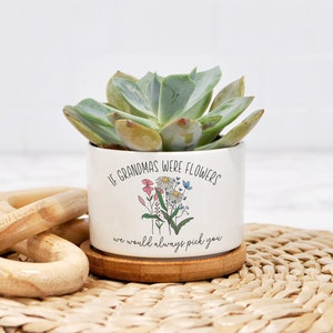 May include: White ceramic succulent planter with the text "If Grandmas were flowers we would always pick you" and a floral illustration. The planter is sitting on a woven straw mat.
