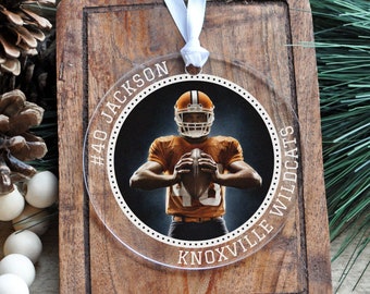 May include: A clear round ornament with a photo of a football player wearing a brown and orange uniform. The ornament has white text that reads "#40 JACKSON KNOXVILLE WILDCATS".
