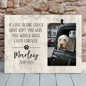 May include: A wooden memorial plaque with a photo of a dog in a car. The text reads "If love alone could have kept you here, you would have lived forever."  The dog's name is Marley and the dates 2014-2023 are printed below.