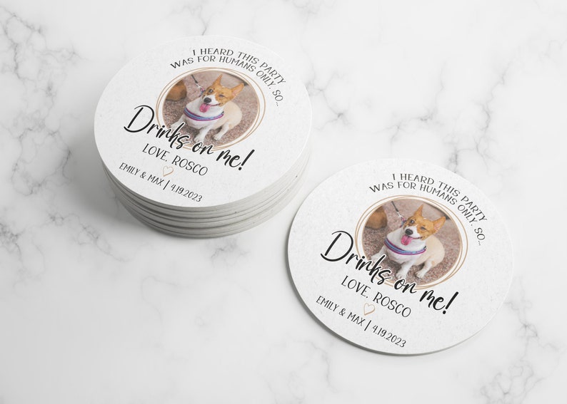 May include: White round paper coasters with a photo of a dog wearing a blue and white striped harness and sunglasses. The text on the coaster reads "I heard this party was for humans only, so... Drinks on me! Love, Roscoe. Emily & Max | 4.19.2023"