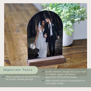 Puede incluir: Una foto de boda mostrada en un soporte de arco de acr&iacute;lico transparente con una base de madera. La foto est&aacute; impresa en la parte posterior del acr&iacute;lico, por lo que se ve a trav&eacute;s.