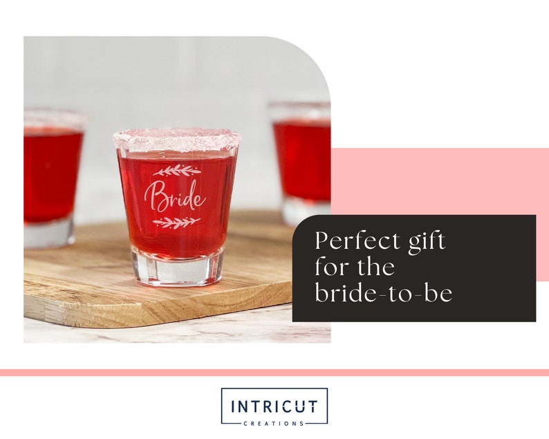 Puede incluir: Vasos de chupito transparentes llenos de l&iacute;quido rojo y con borde de az&uacute;car. La palabra "Bride" est&aacute; grabada en la parte delantera del vaso, con un dise&ntilde;o de hojas. Los vasos est&aacute;n sobre una tabla de cortar de madera.