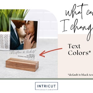 May include: A clear acrylic photo display with a wooden base. The display features a couple's photo and text that reads "Christine & Robert, YES TODAY, YES TOMORROW, YES FOR ALL THE DAYS OF MY LIFE, 08.24.22". Additional text on the right says "what can I change? Text Colors*" with "*default is black text".
