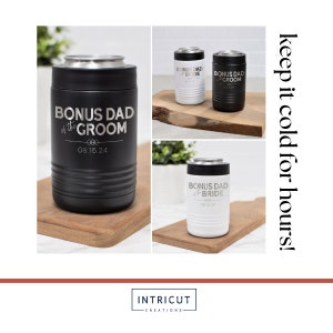 May include: Three stainless steel can coolers with personalized engravings. The coolers are black, white, and black with a white top. The engravings read "Bonus Dad of the Groom" and "Bonus Dad of the Bride" with a date. The coolers are on a wooden surface.