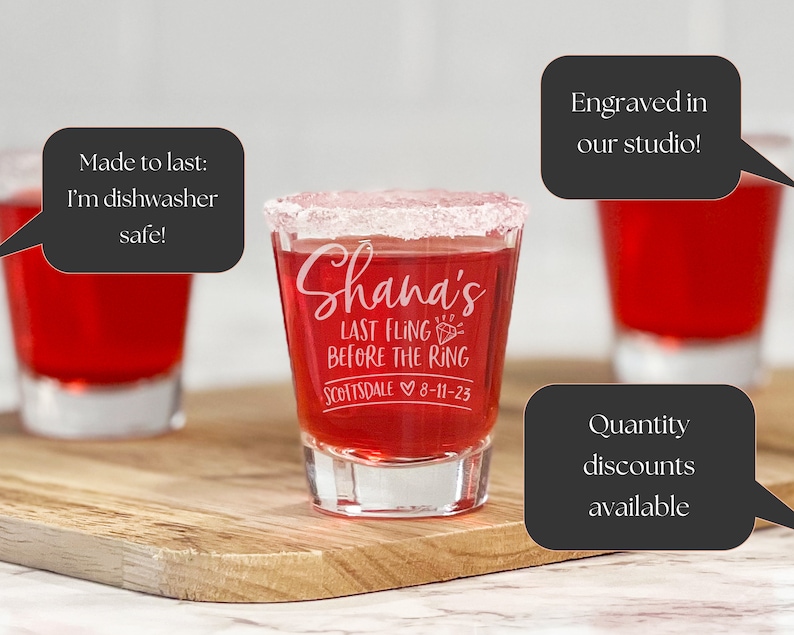 Puede incluir: Vasos de chupito llenos de l&iacute;quido rojo, con borde blanco y grabados con texto. El vaso central dice "Shana's LAST FLING BEFORE THE RING Scottsdale 8-11-23". Los vasos est&aacute;n sobre una tabla de madera.