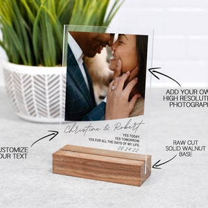 May include: A clear acrylic photo display with a raw-cut solid walnut base. The display features a photograph of a couple and includes the text "Christine & Robert" and the date "08.24.22". The text "Customize Your Text" is also visible.