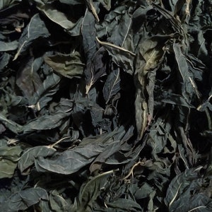 Può includere: Primo piano di un mucchio di foglie secche di colore verde scuro. Le foglie sono disposte in modo casuale e sono tutte di dimensioni e forma simili.