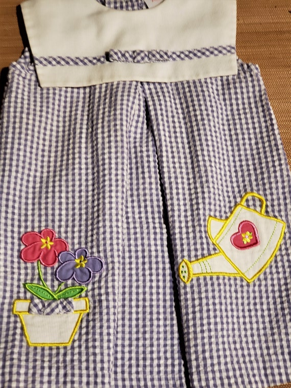 with decrotive watering pot An adorable little girl grape blue vintage gingham dress Free Shipping and a flower pot of daisy flowers.
