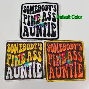 May include: Embroidered patches with the text "SOMEBODY'S FINE ASS AUNTIE" in a square shape. The top patch is black and white, while the other two have brown, yellow, and orange color schemes. The patches are likely for clothing or accessories.
