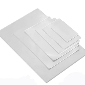 May include: A set of five clear plastic sheets of varying sizes, stacked on top of each other.