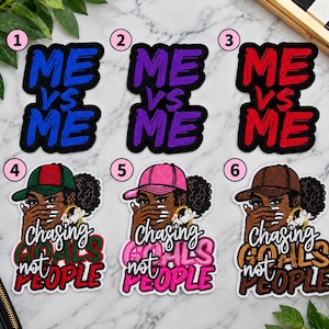 May include: Six embroidered patches arranged in two rows. The top row features the text ME VS ME in blue, purple, and red. The bottom row shows a person wearing a cap, with the text Chasing GOALS not PEOPLE in green, pink, and brown color schemes.