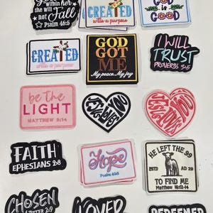 May include: A collection of embroidered fabric patches featuring various religious phrases and scripture references. The patches are rectangular, heart-shaped, or custom-cut with black, white, pink, and gold thread designs on diverse backgrounds.